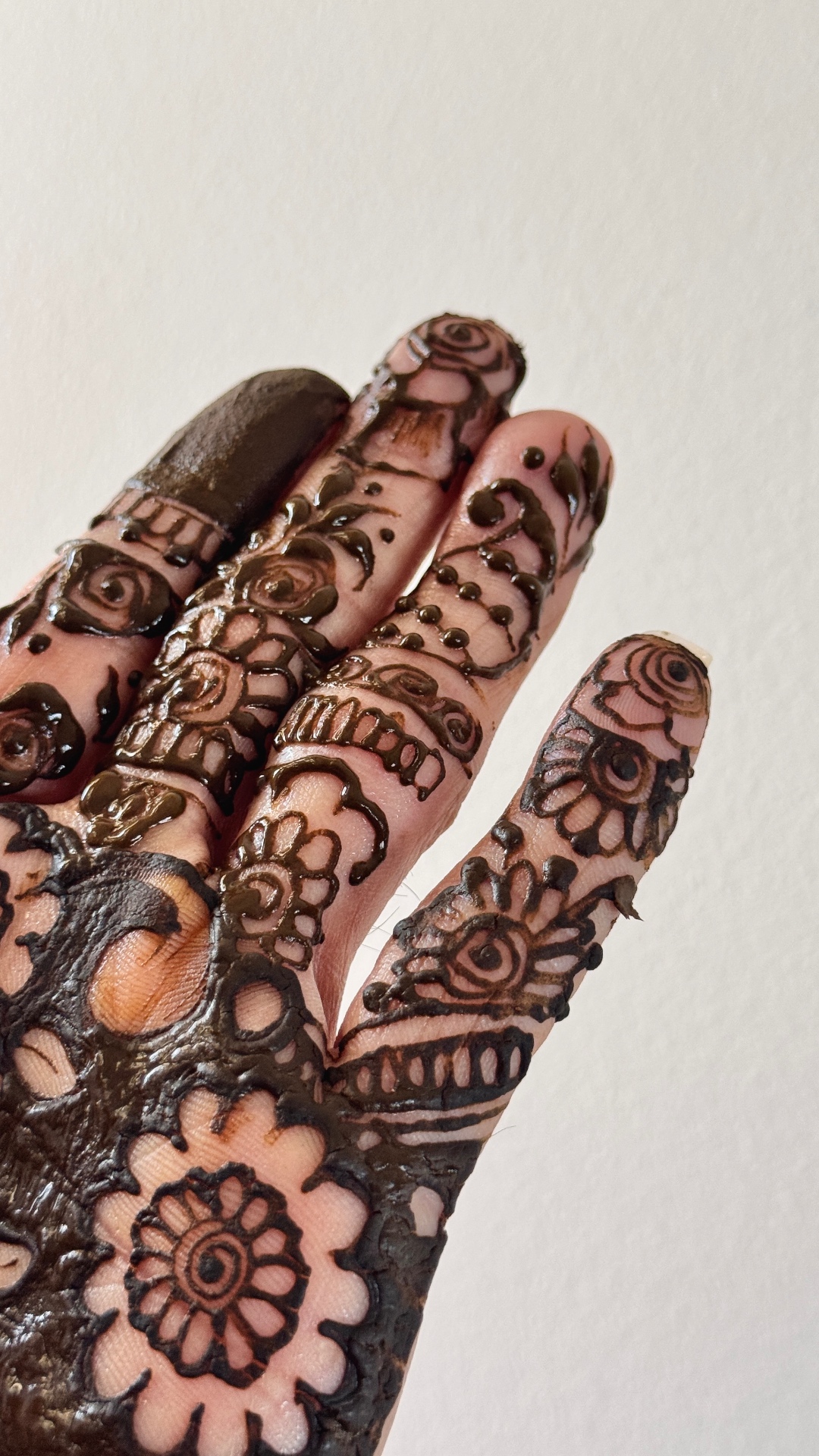 Fresh henna paste application showing intricate finger patterns
